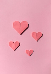 Pink paper origami hearts on the pink background. Valentine's day celebration concept