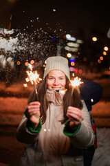 Girl with sparklers on the street at night in winter time.