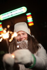 Girl with sparklers on the street at night in winter time.