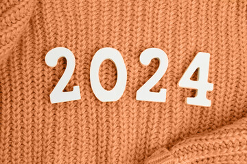 Wooden numbers 2024 and  on a peach knitted background. Festive background. Peach Fuzz Color of...