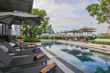Luxury rooftop pool with lounge chairs in modern urban hotel. Urban relaxation.