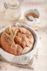 Fresh loaf of round bread with grain and ears.