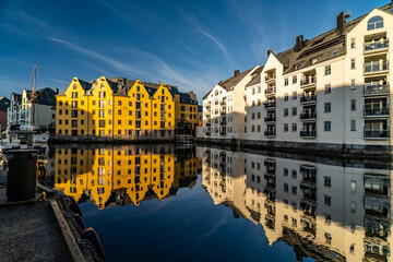 alesund canal with colorful buildings reflected in water in norway