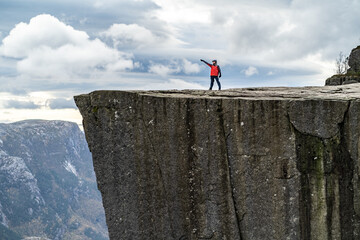 alone man in red coat on Preikestolen pulpit rock in norway