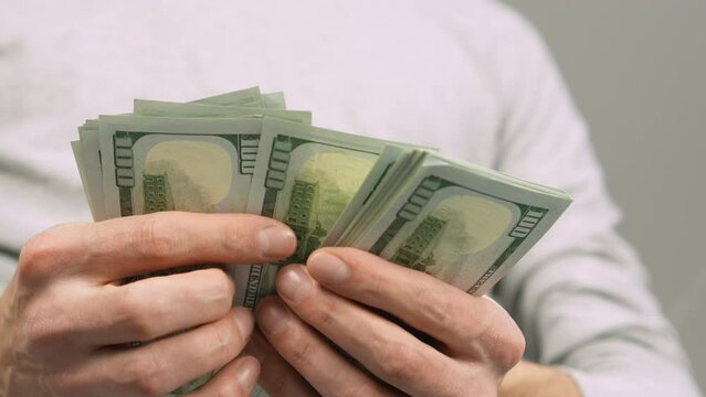 A man in his hands holds a pack of hundred-dollar bills and counts them. This video offers you a glimpse into the financial ecosystem, where smart money management plays an important role in one's own