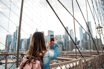 Woman capturing Manhattan skyline from Brooklyn Bridge