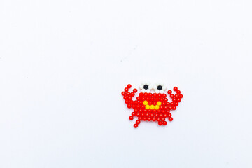Figure of a colorful red crab made of wood by a child, white background