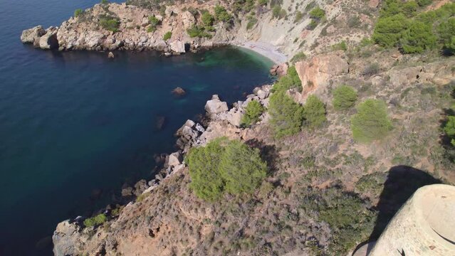 Seaside cliffs and medieval towers. Revealing aerial view of the beach with turquoise waters. Mediterranean Sea. Spain.
