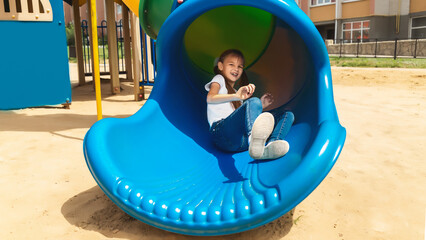Fototapeta na wymiar Happy child girl sliding and playing at outdoor playground in the park, outdoor activity playground