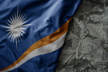 waving flag of Marshall Islands on the old khaki texture background. military concept.