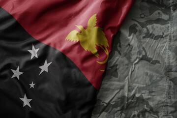 waving flag of Papua New Guinea on the old khaki texture background. military concept.