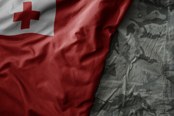 waving flag of Tonga on the old khaki texture background. military concept.