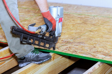 In installation of wooden plywood floor new home using air nail gun