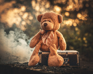Teddy Bär sitzt auf einem Koffer am Bahnhof