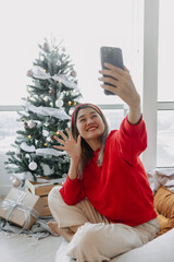 Happy red shirt woman making a video call holiday greeting with her friends and family showing the...
