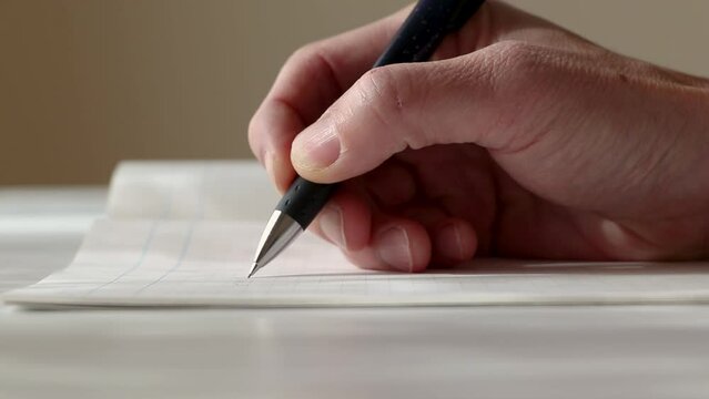 考えながらノートに何か書く男性の手