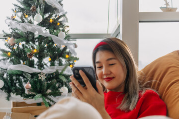 Happy woman in red sweater call and chat on the phone to merry her friends and family in Christmas...