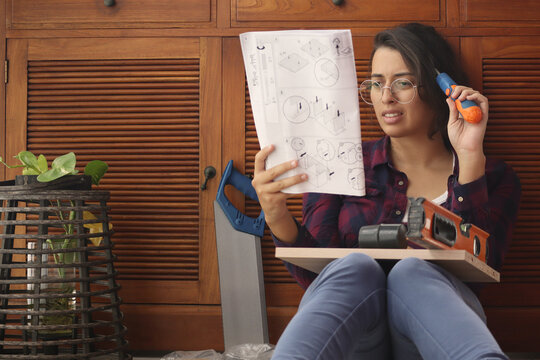 Jeune femme avec une notice de montage complexe et des outils de bricolage