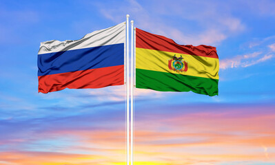 Russia and Bolivia two flags on flagpoles and blue sky.