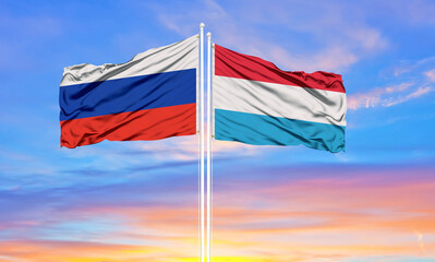 Russia and Luxembourg two flags on flagpoles and blue sky.