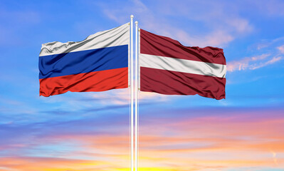 Russia and Latvia two flags on flagpoles and blue sky