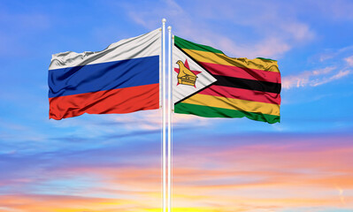 Russia and zimbabwe two flags on flagpoles and blue sky.