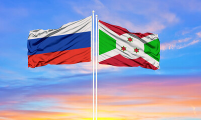 Russia and Burundi two flags on flagpoles and blue sky.