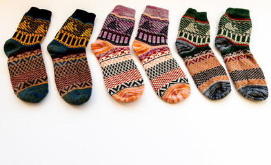 A row of colourful Winter woollen socks of various patterns isolated in a white background.