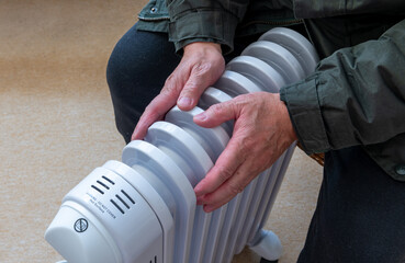A person sitting in a room hugging a portable electric heater trying to keep warm in the Winter...