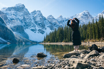 Moraine lake in autumn sunny day morning with snow-capped mountains. Tourists enjoying the beautiful scenery in Banff National Park, Canadian Rockies. Alberta, Canada.