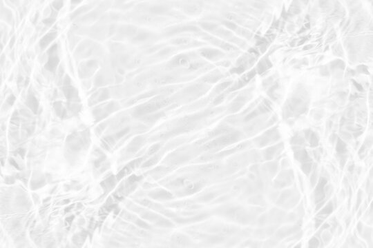 White water with ripples on the surface. Defocus blurred transparent white colored clear calm water surface texture with splashes and bubbles. Water waves with shining pattern texture background.