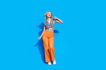 Full length photo of gorgeous woman dressed print blouse orange pants enjoy party dancing isolated on bright blue color background