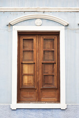 Wooden door. Peeling paint wood. Home exterior facade. Single wood frame isolated on wall. Closed window shutter. Balcony door isolated.
