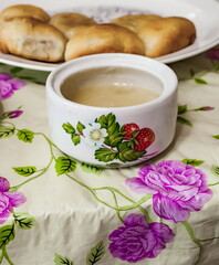 Ceramic dishes with honey close-up on the background of a plate with pies and a colored tablecloth