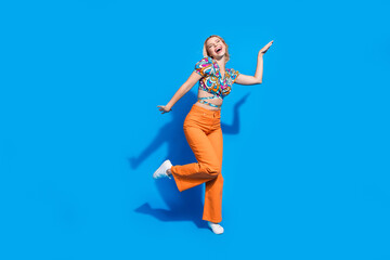 Full length photo of funky eccentric woman dressed print blouse orange pants having fun dancing isolated on bright blue color background