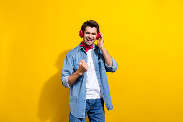 Photo portrait of attractive young man touch headphones raise fist sing dressed stylish denim...
