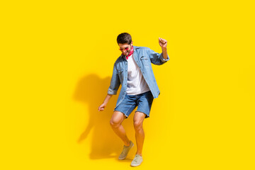 Fototapeta premium Full body photo of positive man dressed denim shirt shorts in glasses celebrate big sale dancing isolated on yellow color background