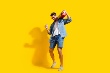 Full body photo of eccentric man dressed denim shirt shorts in glasses dance with boombox on shoulder isolated on yellow color background