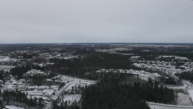 Aerial footage of a residential neighborhood and dense trees covered with snow at susnet