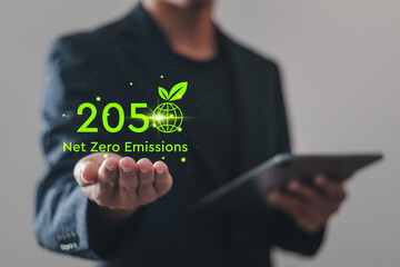 Net zero emissions by 2050. Businessman holding virtual Net Zero icon to change climate and net zero greenhouse gas emissions target. Sustainable development and green business concept. - obrazy, fototapety, plakaty