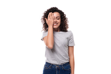 positive confident bright young european slim brunette woman with curly hair style dressed in a gray t-shirt on a white background with copy space