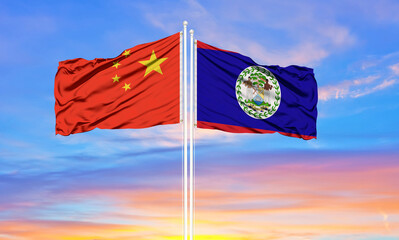 China and Belize two flags on flagpoles and blue cloudy sky . Diplomacy concept, international relations