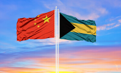 China and Bahamas two flags on flagpoles and blue cloudy sky . Diplomacy concept, international relations