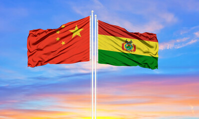 China and Bolivia two flags on flagpoles and blue cloudy sky . Diplomacy concept, international relations