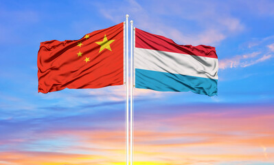 China and Luxembourg two flags on flagpoles and blue cloudy sky . Diplomacy concept, international relations