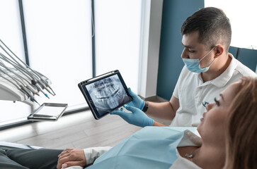 The dentist carefully examines the condition of the patient's oral cavity on CT and MRI images and...
