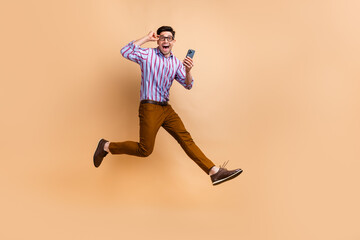 Fototapeta na wymiar Full length photo of overjoyed cheerful guy wear stylish clothes running empty space isolated on beige color background
