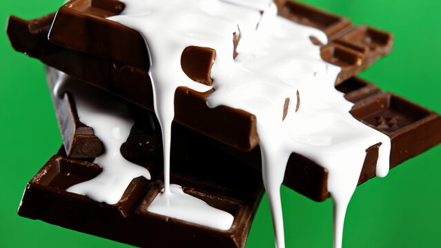 Close up of chocolate bars with draining white glaze isolated on chroma key green wall background. Stock clip. Black chocolate and white glaze.