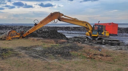 a dirty excavator in the mud lake for arranging the mud to make the dam stronger and higher 