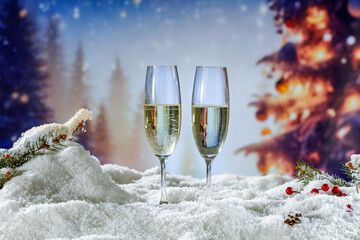 Two glasses of champagne on table cover of snow with frost and blurred background of New Year time...